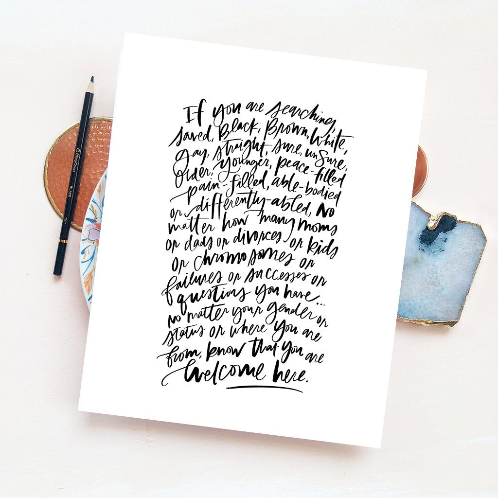 styled inspiration photo of welcome here manifesto calligraphy artwork in white